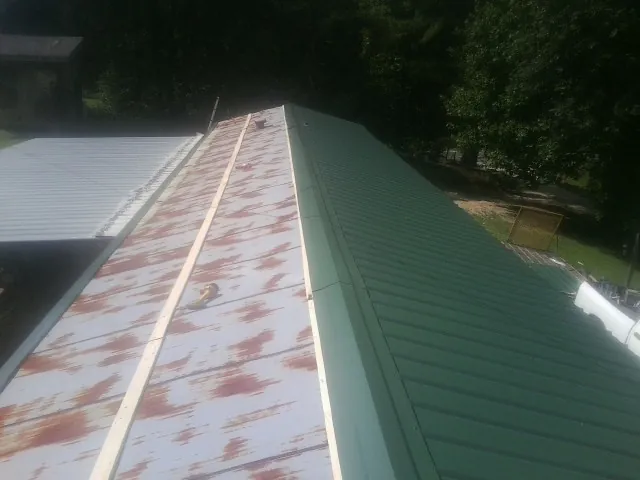 Old rusted panels beside newly installed green metal roofing — Wind Damage Roof Repair by Roofing Brothers in Commerce City