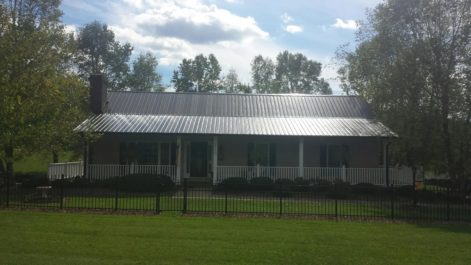 Gray metal roof on a brick ranch with a full width front porch — Gutter Guard Installation work by our crew in Commerce City