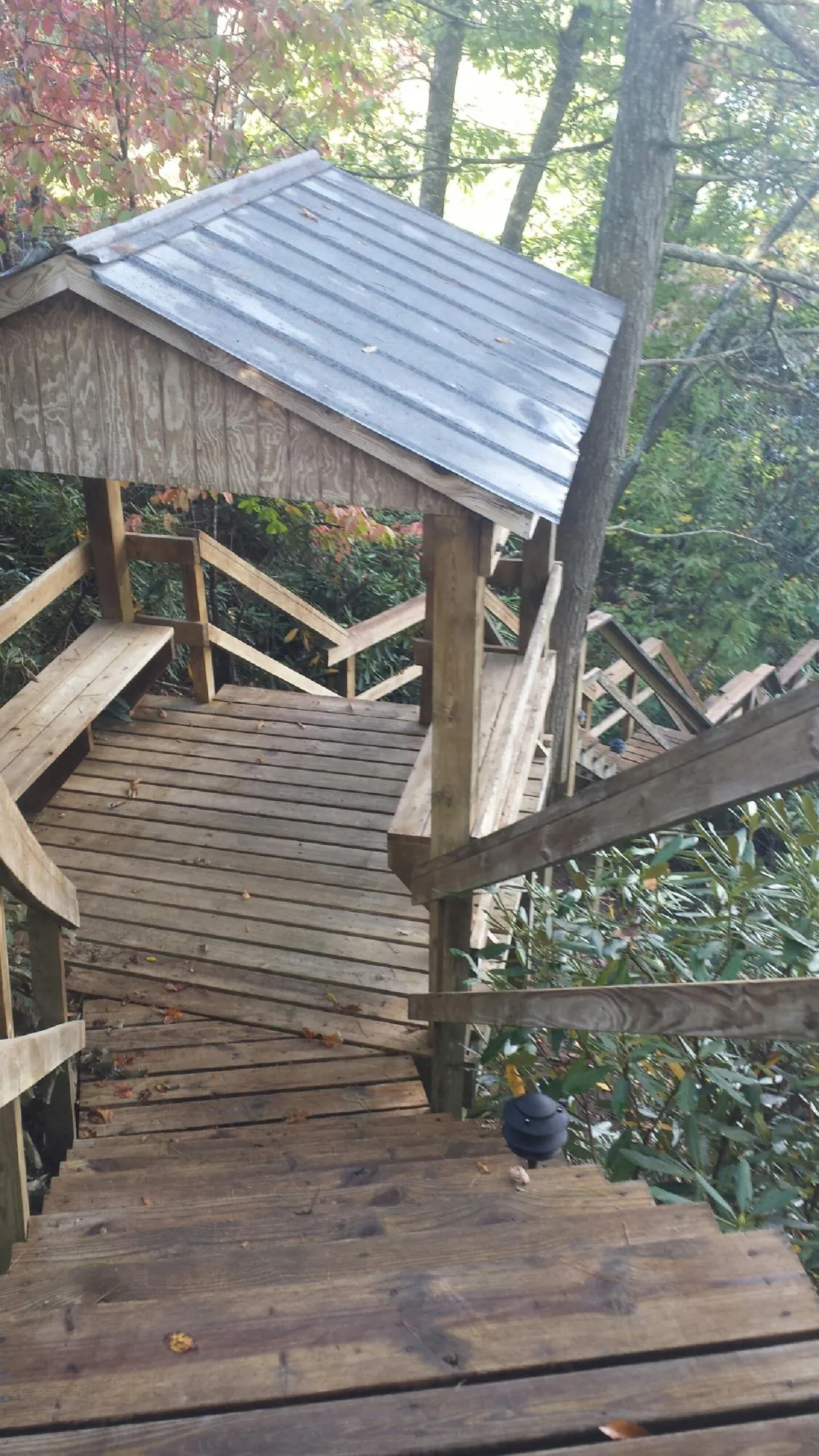 Metal roofed shelter over wooden steps on a wooded walkway — Skylight Repair & Installation work by our crew in Commerce City