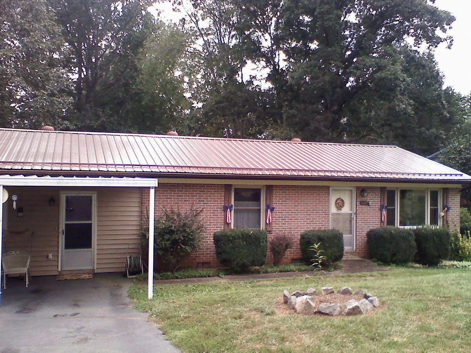 Bronze metal roof and carport on a brick ranch home — Roof Repair work by our crew in Commerce City