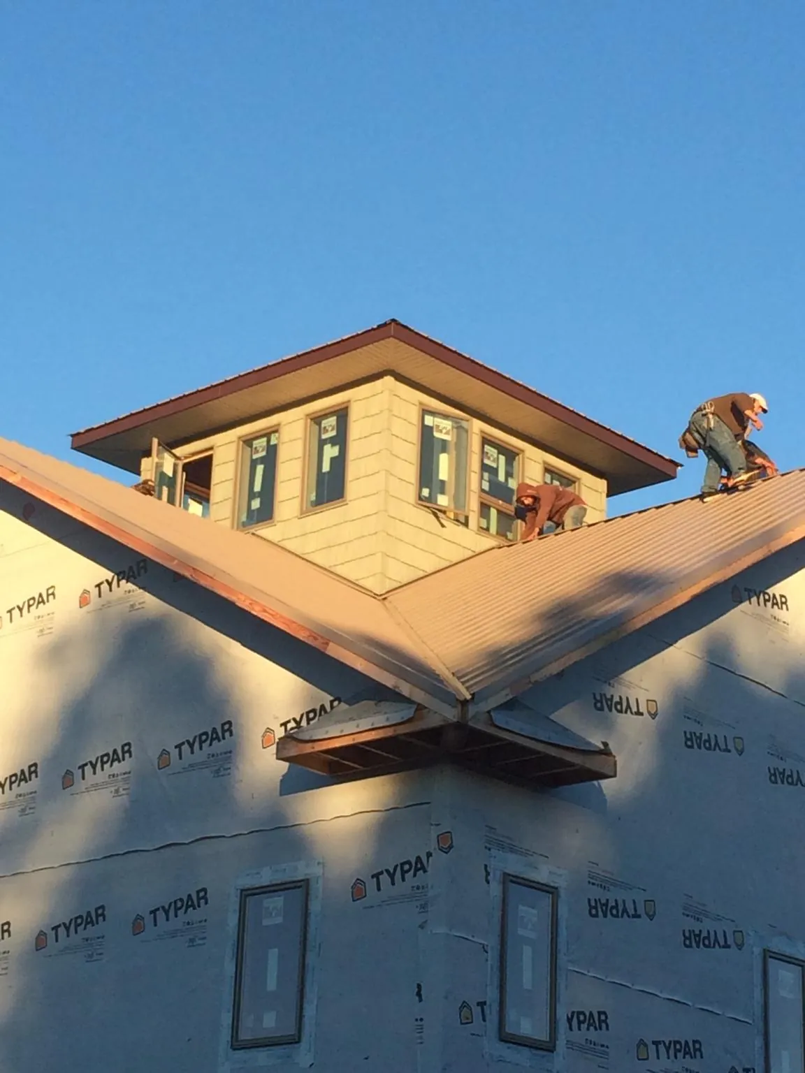 Roofers working around a rooftop cupola on a new metal roof at sunset — Roof Waterproofing in Commerce City by Roofing Brothers